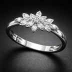 Silver ring with diamond flower design on a dark background