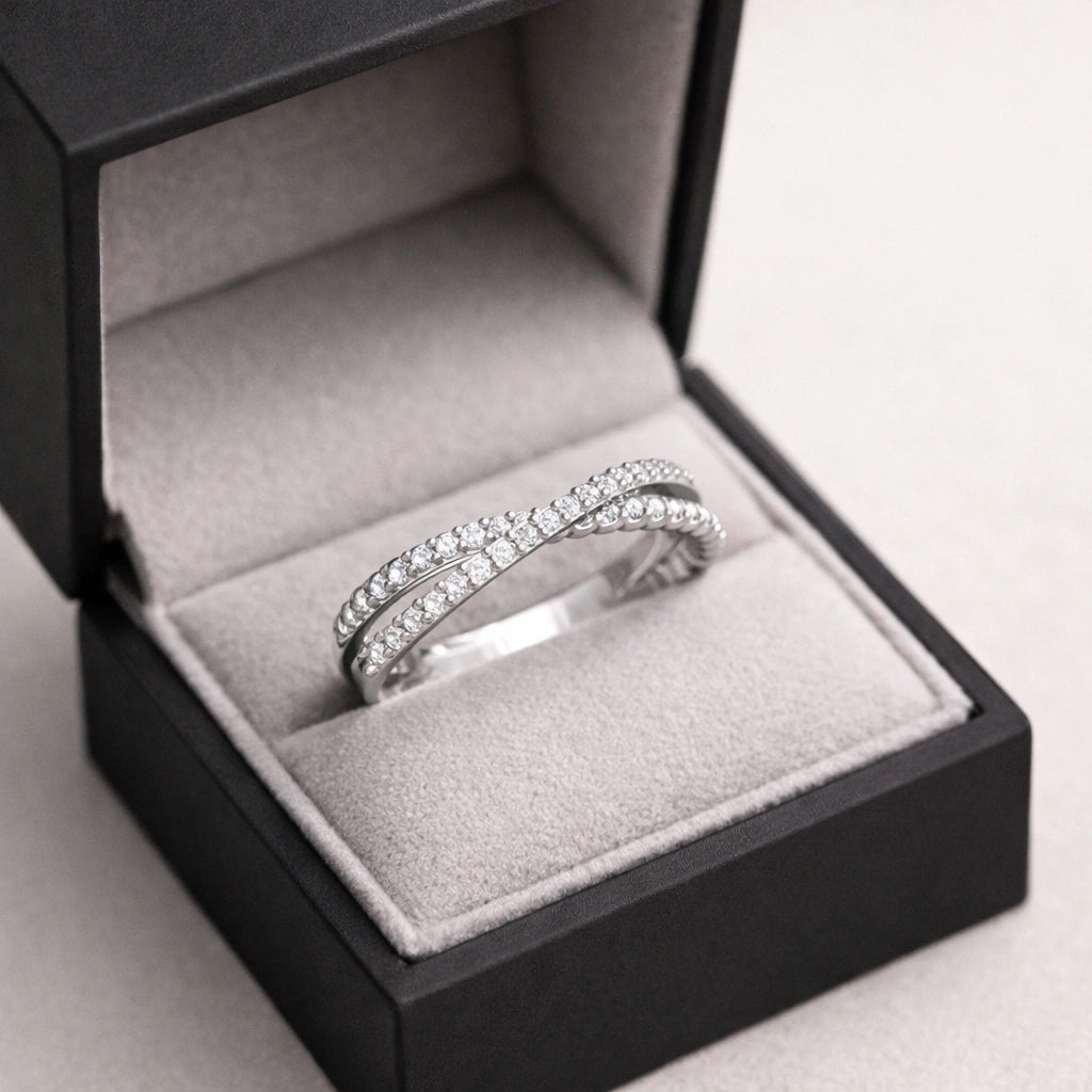 Silver ring with diamonds in an open jewelry box on a light gray background