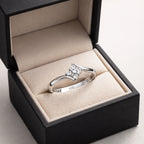 Silver ring with diamonds in a black box on a light gray background