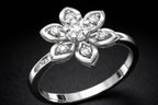 Silver ring with diamond flower design on a dark background