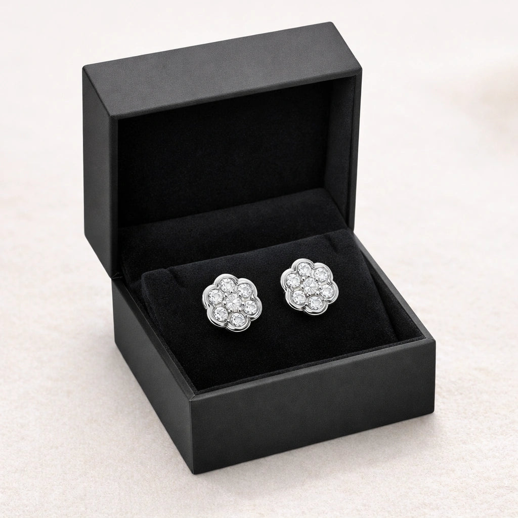 Pair of silver floral earrings in an open black jewelry box on a light background