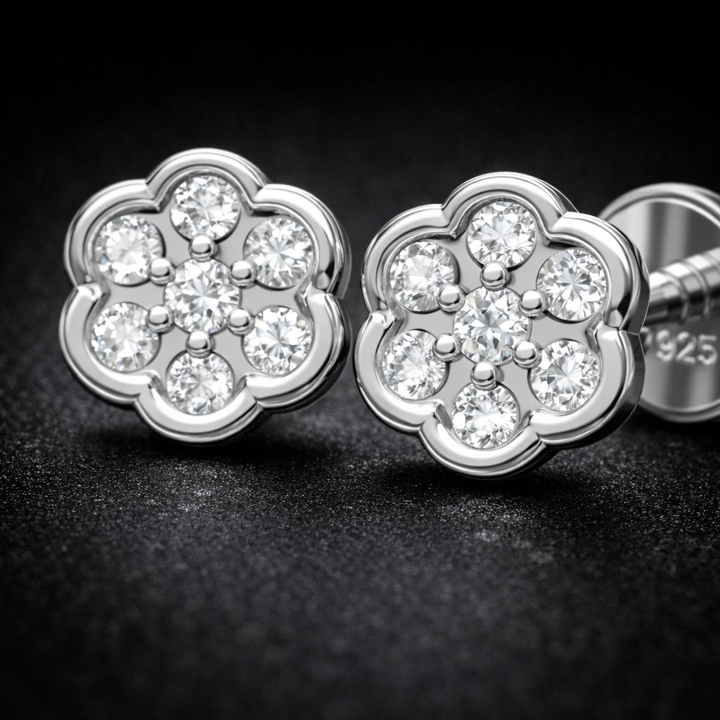 Silver flower-shaped earrings with clear gemstones on a dark background