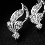 Silver earrings with diamond-like stones on a dark background