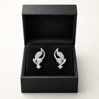 Pair of silver earrings with gemstones in a black jewelry box on a white background