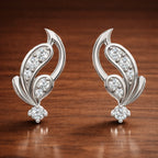 Pair of silver earrings with diamond accents on a wooden surface