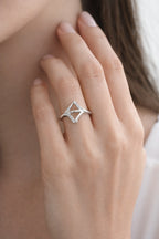 Silver ring with a geometric design on a person's finger