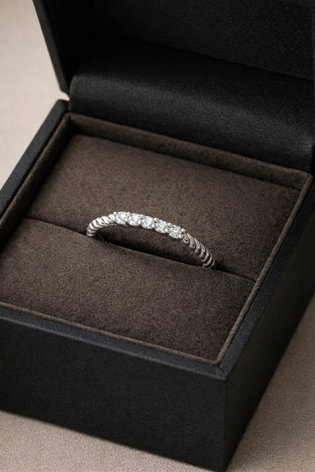 Diamond ring in a black jewelry box on a neutral background