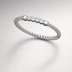 Silver ring with small diamonds on a light gray background