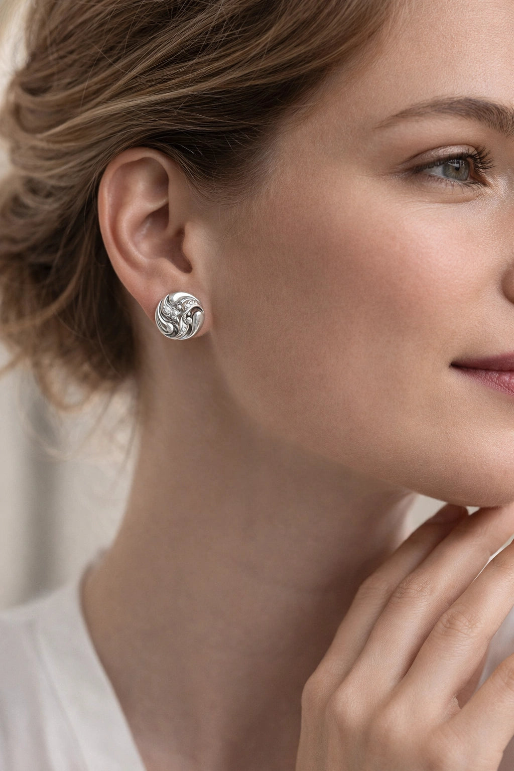 Close-up of a woman wearing silver earrings with a neutral background