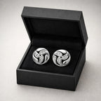Silver cufflinks with gemstones in a black box on a light gray background