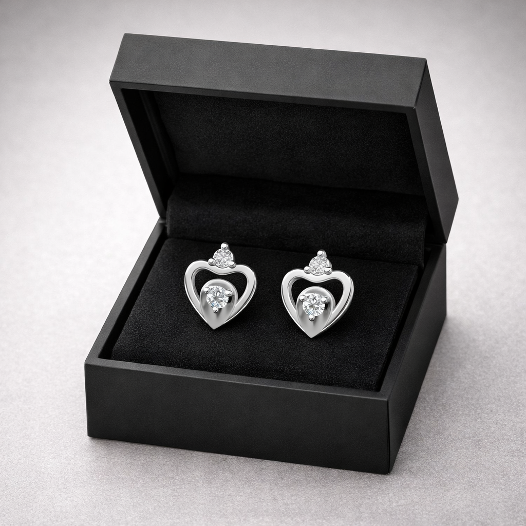 Heart-shaped silver earrings in a black jewelry box on a light gray background