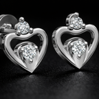 Heart-shaped silver earrings with clear gemstones on a black background