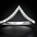 Silver triangle-shaped ring with embedded stones on a dark background