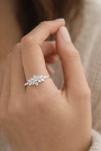 Close-up of a hand wearing a silver ring with a leaf-like design.