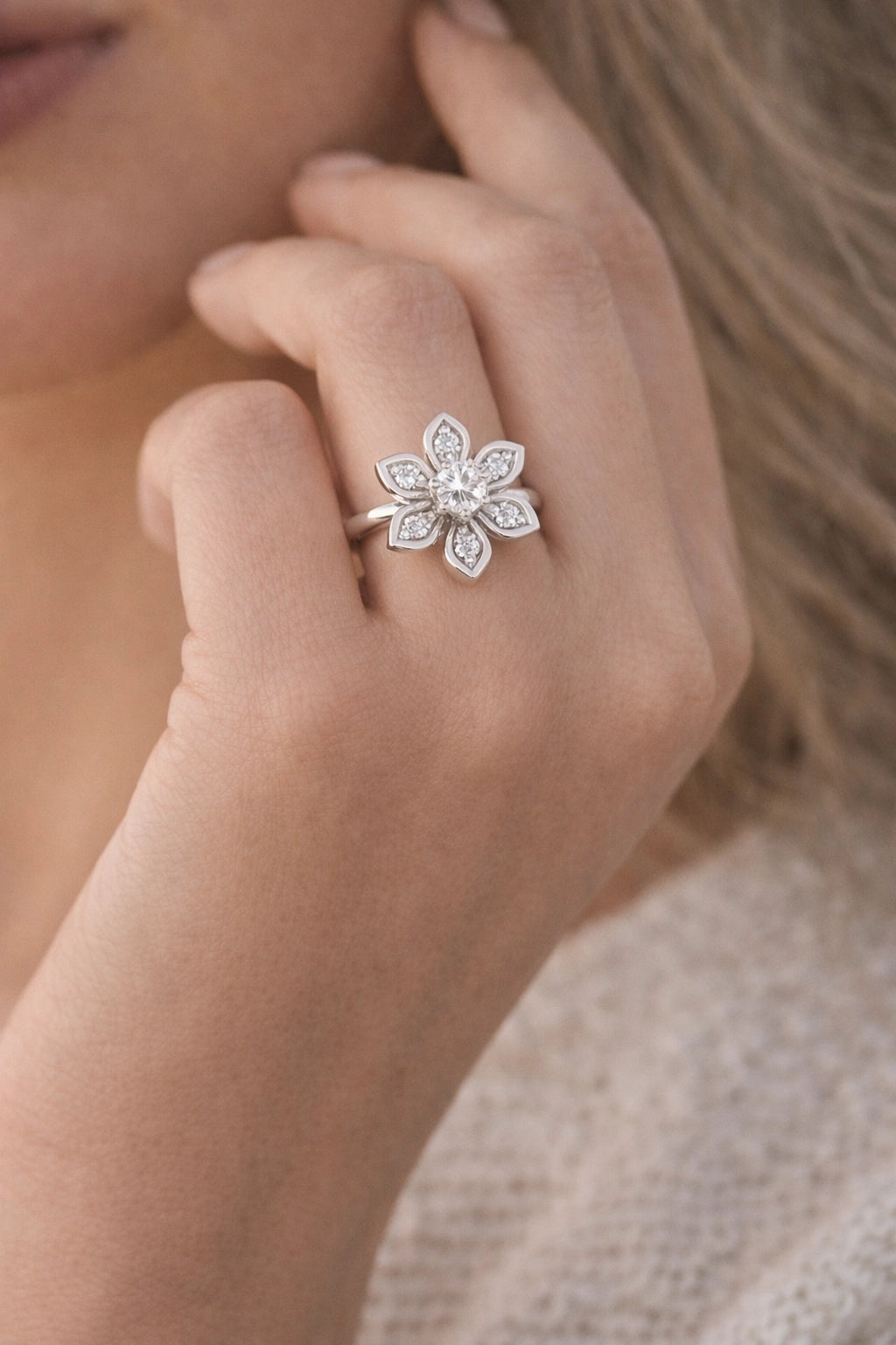 Close-up of a hand wearing a silver floral ring with diamonds.