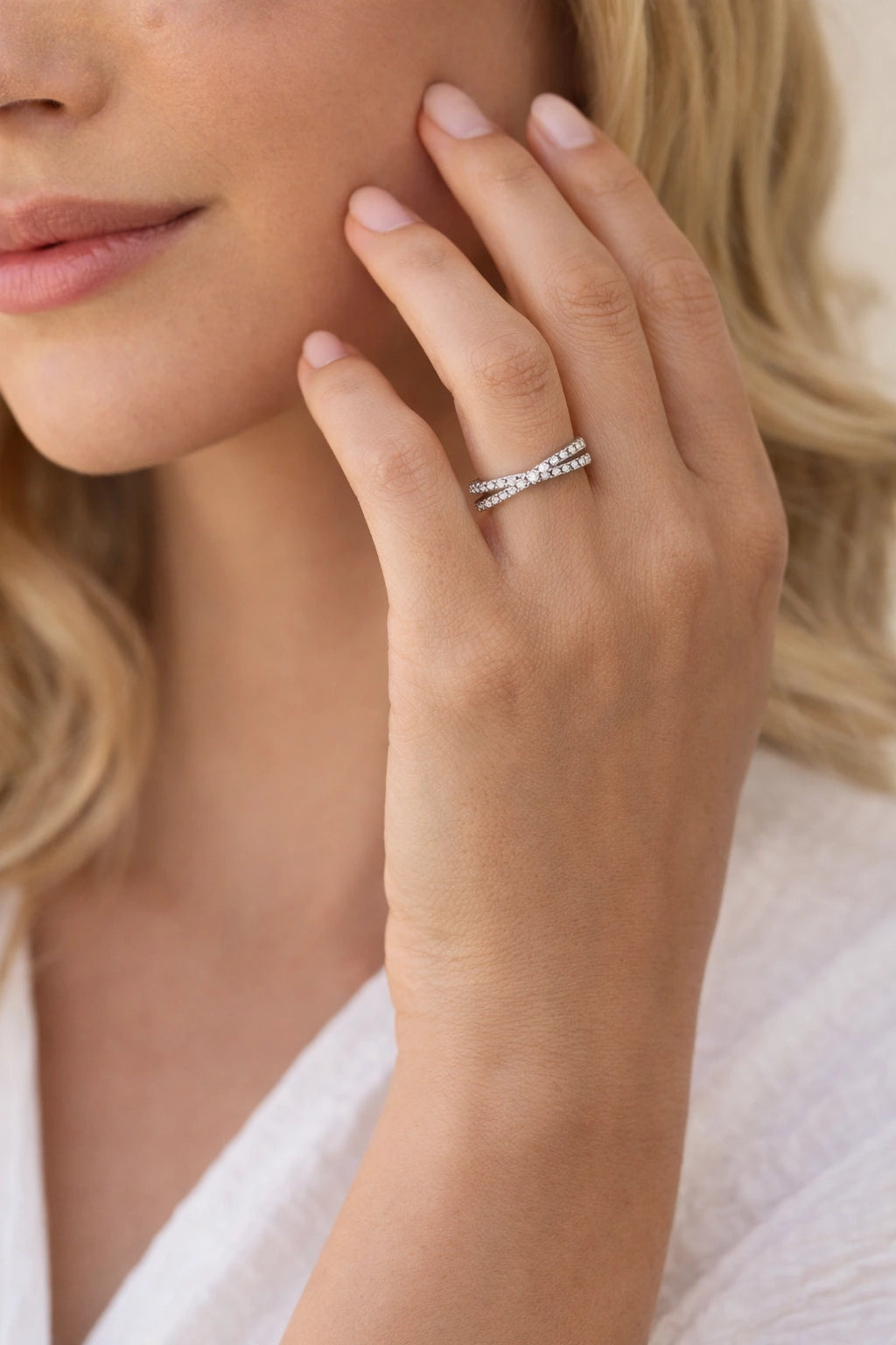 Close-up of a hand wearing a silver ring with a diamond, against a neutral background.
