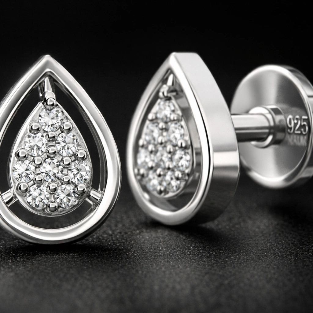 Silver teardrop-shaped earrings with clear gemstones on a dark background