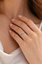Close-up of a hand wearing a diamond ring on a blurred background