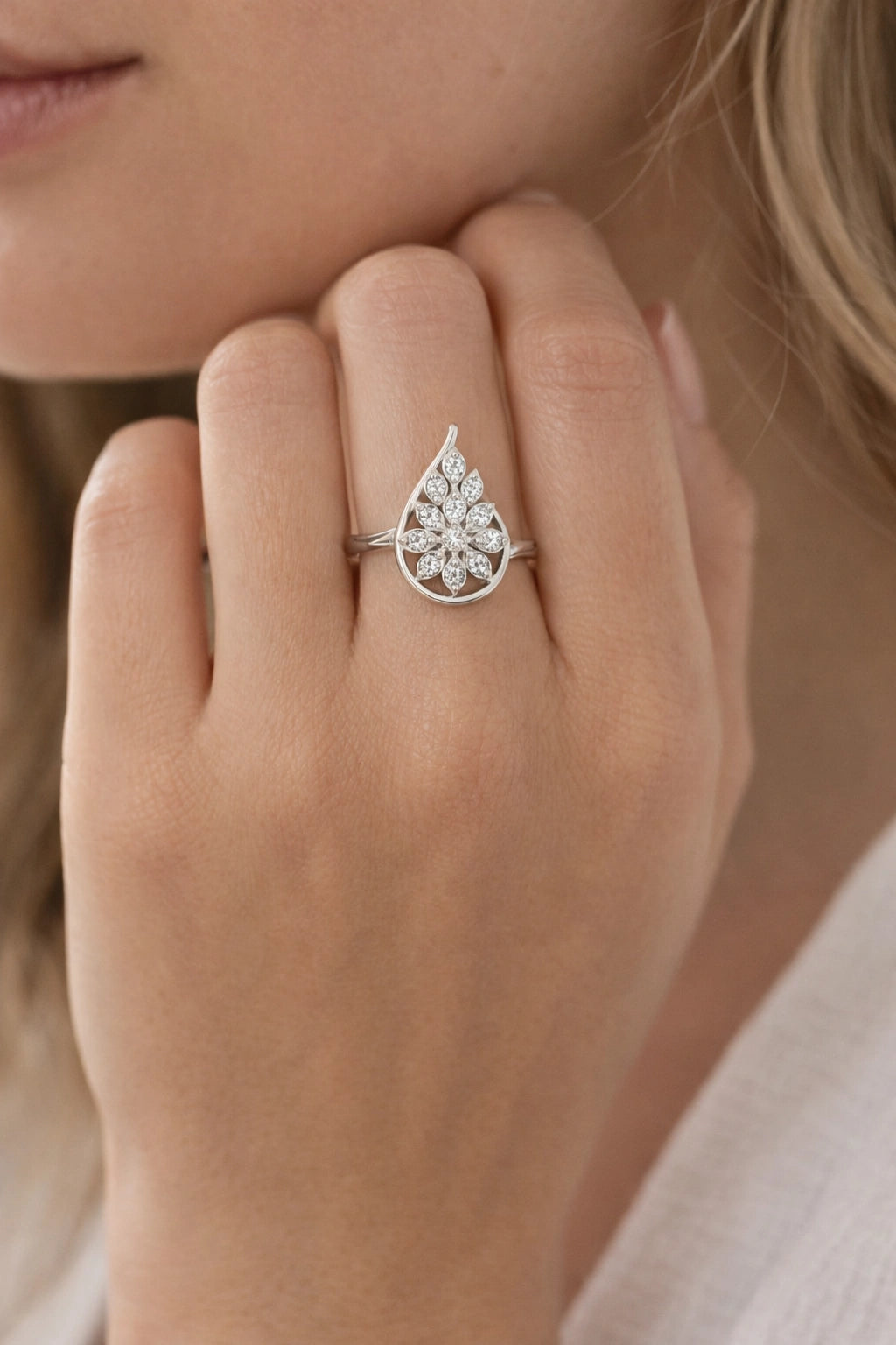 Silver teardrop-shaped ring on a hand with a blurred background