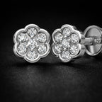 Silver flower-shaped earrings with clear gemstones on a dark background