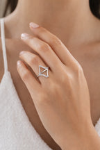 Close-up of a hand wearing a diamond ring with a triangle design.