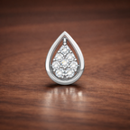 Teardrop-shaped silver pendant with clear stones on a wooden surface