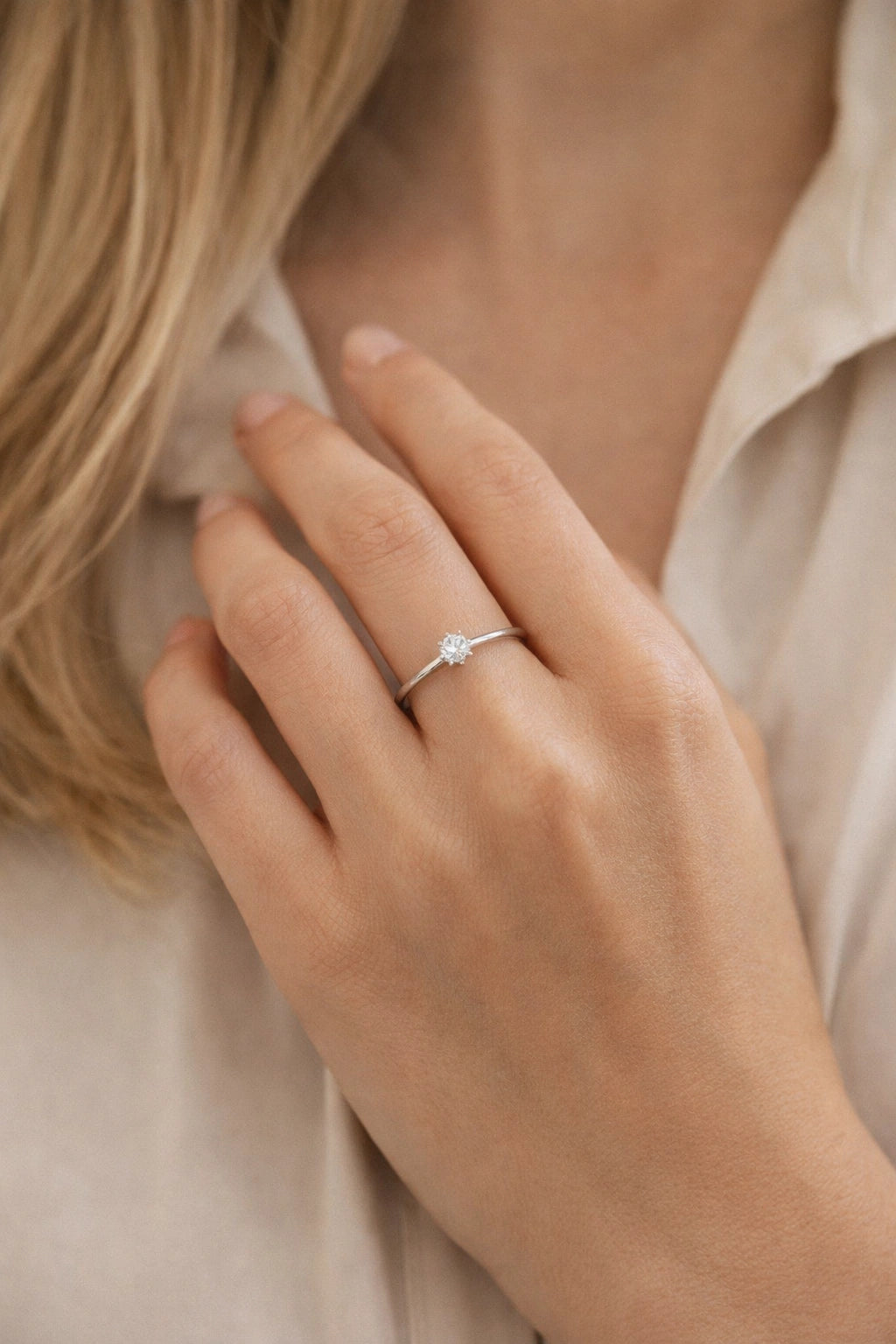 Close-up of a hand wearing a ring with a blue gemstone, set against a neutral background.