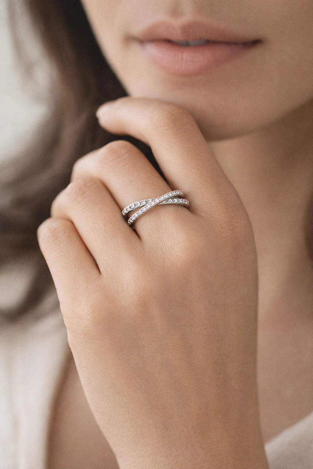 Close-up of a hand wearing two silver rings with a soft background